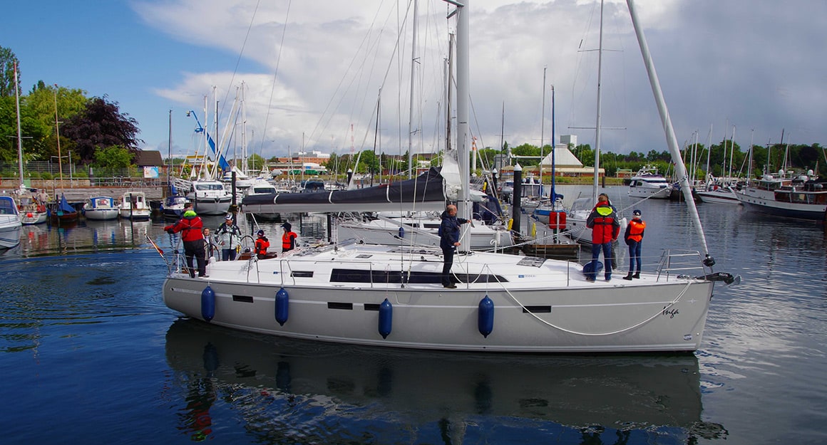 Segelyacht beim Hafenmanöver mit Crew an Deck